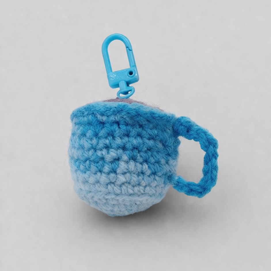Crocheted blue mug charm with a keyring on a light gray background